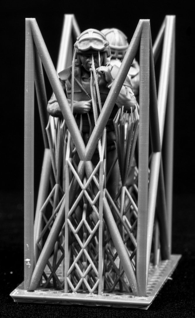 Two miniature figures of soldiers with gear inside a frame on a black background