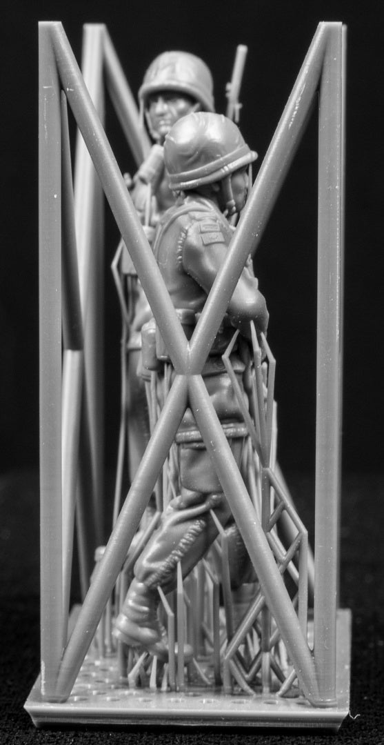 Two miniature figures of soldiers with gear inside a frame on a black background