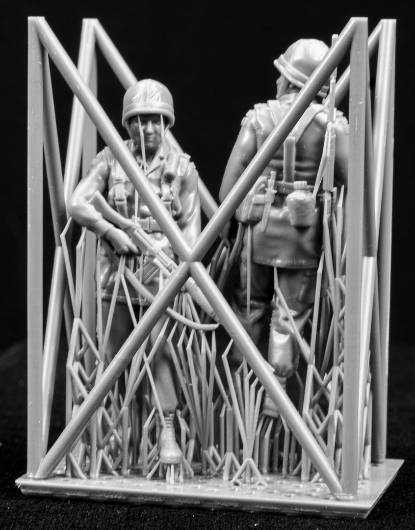 Two miniature figures of soldiers with gear inside a frame on a black background