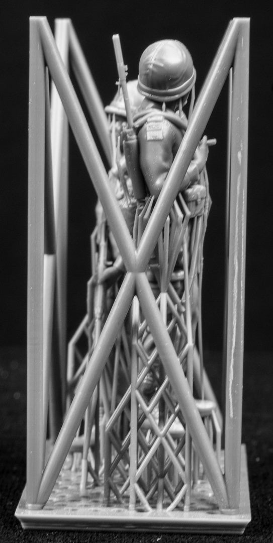 Two miniature figures of soldiers with gear inside a frame on a black background