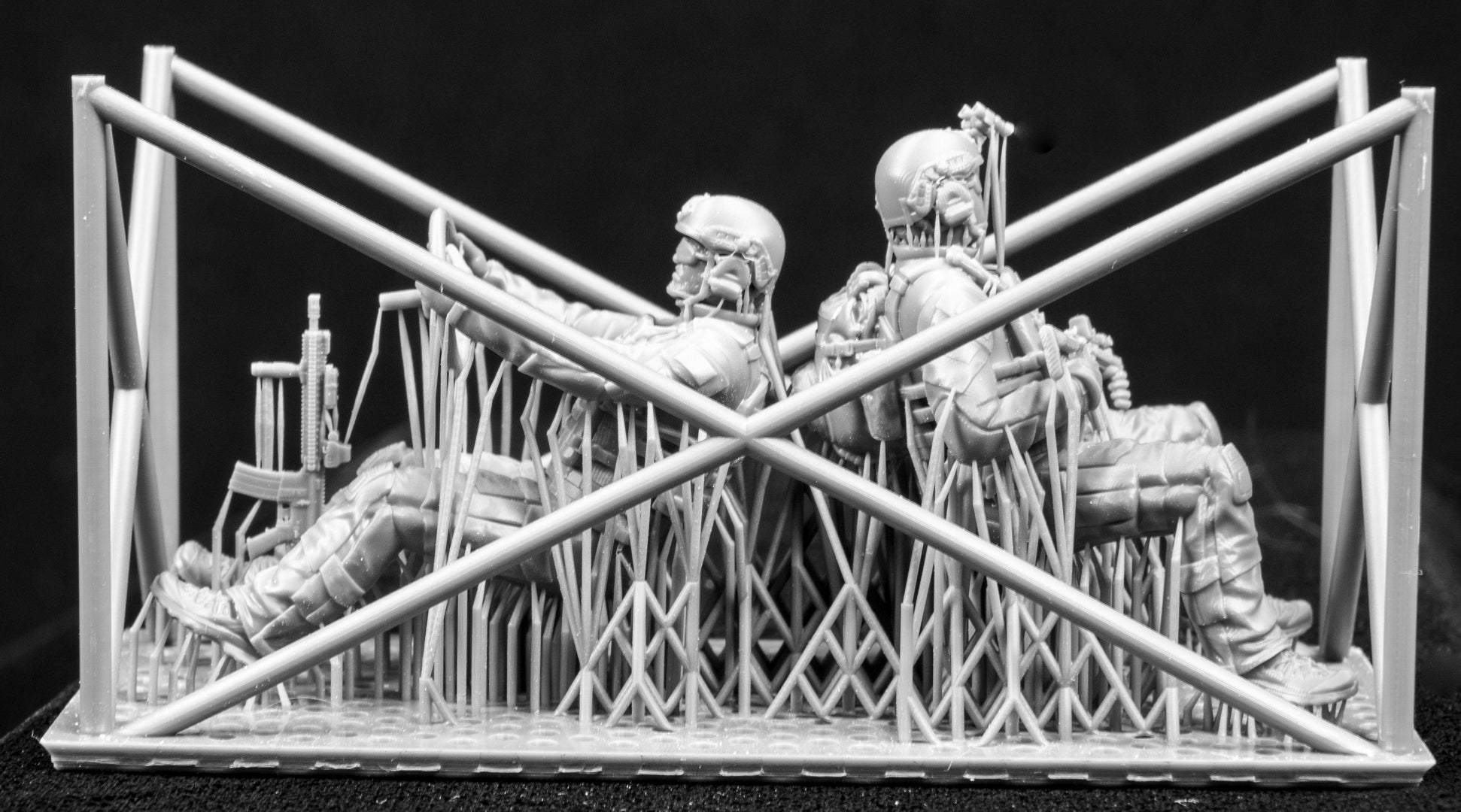 Two 3D Printed figures on a frame set on a black background.