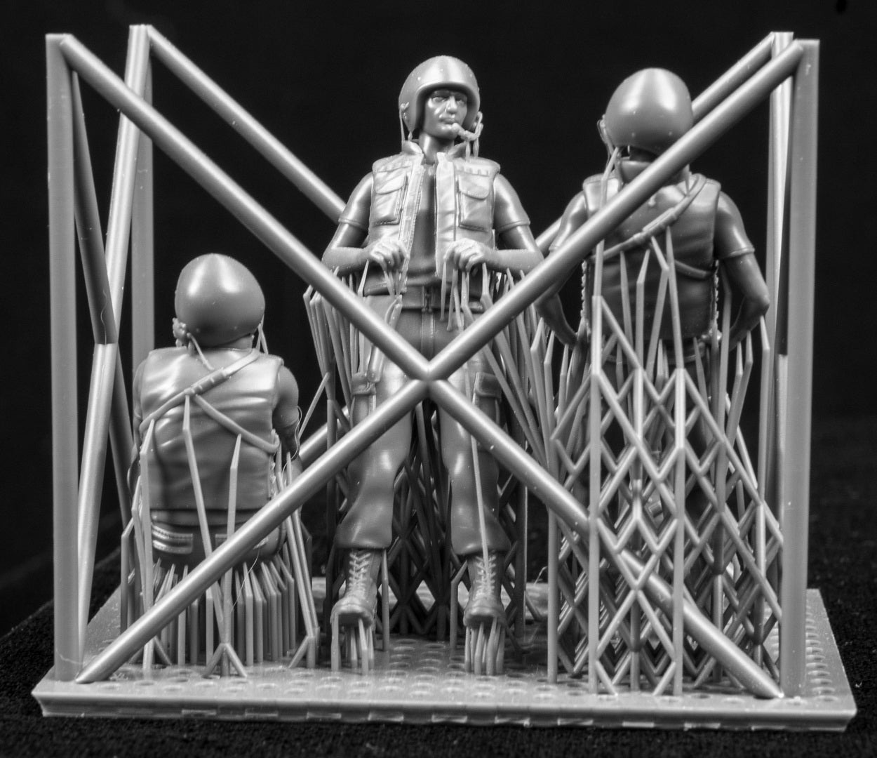 Three  miniature figures in a cradle on a black background