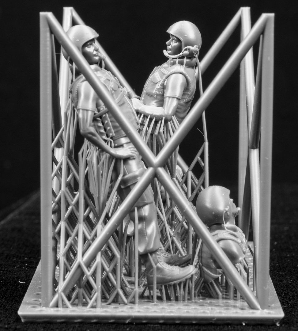 Three  miniature figures in a cradle on a black background