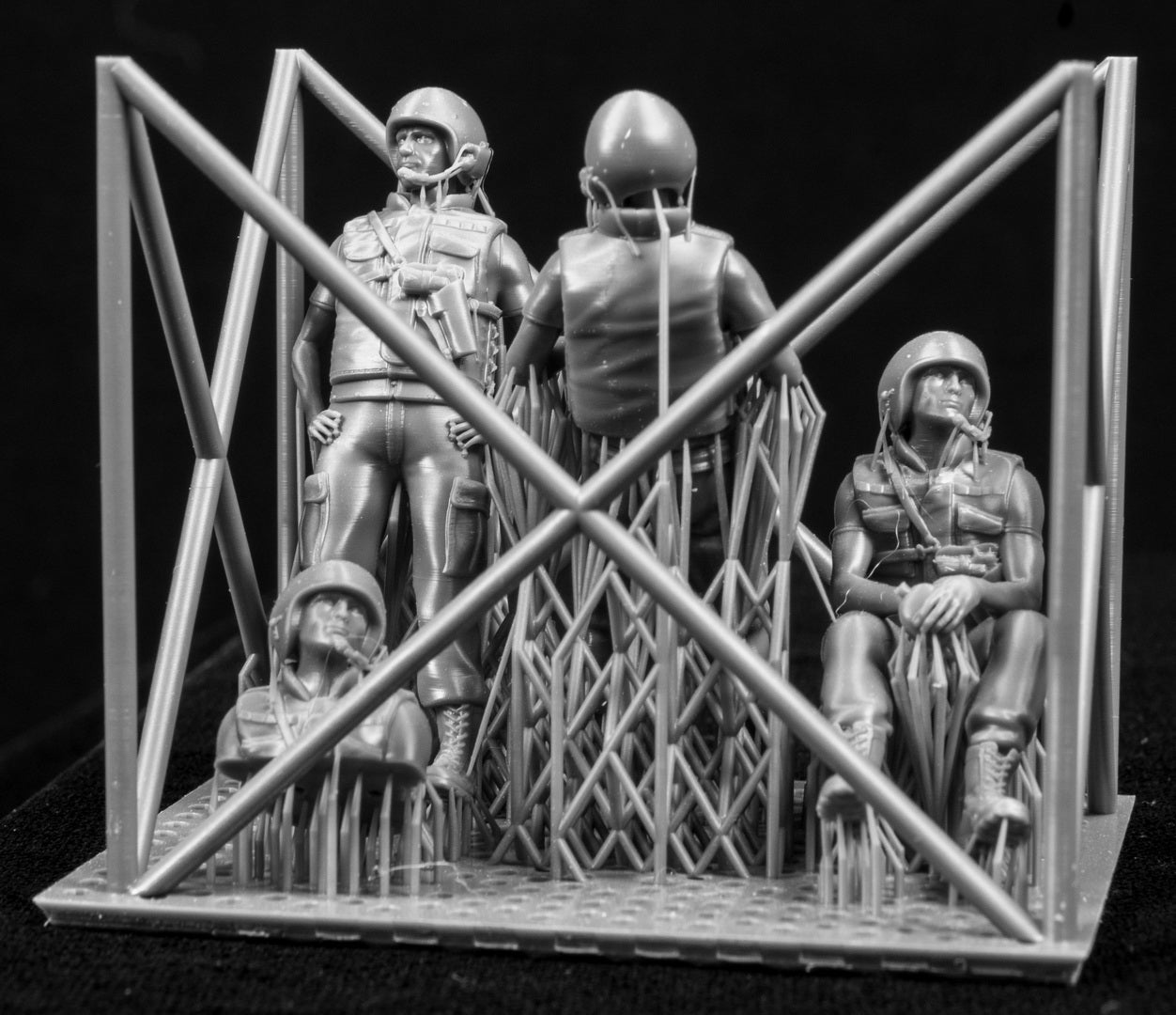 Three  miniature figures in a cradle on a black background