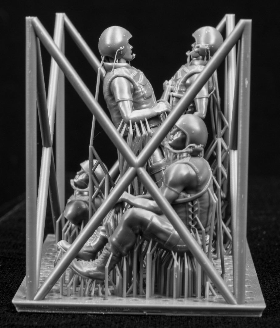 Three  miniature figures in a cradle on a black background