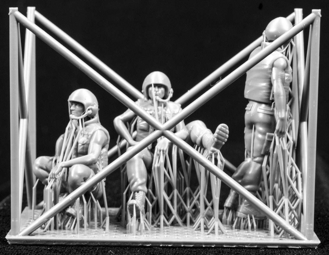 Three miniature figures in a cradle on a black background
