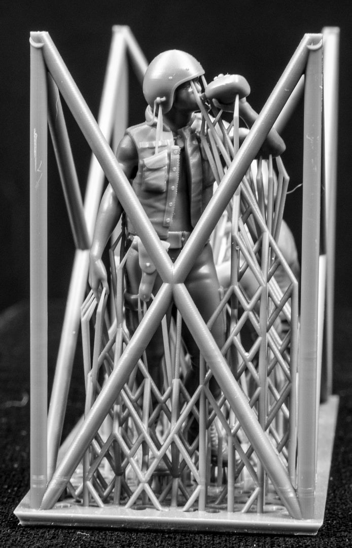 Three miniature figures in a cradle on a black background
