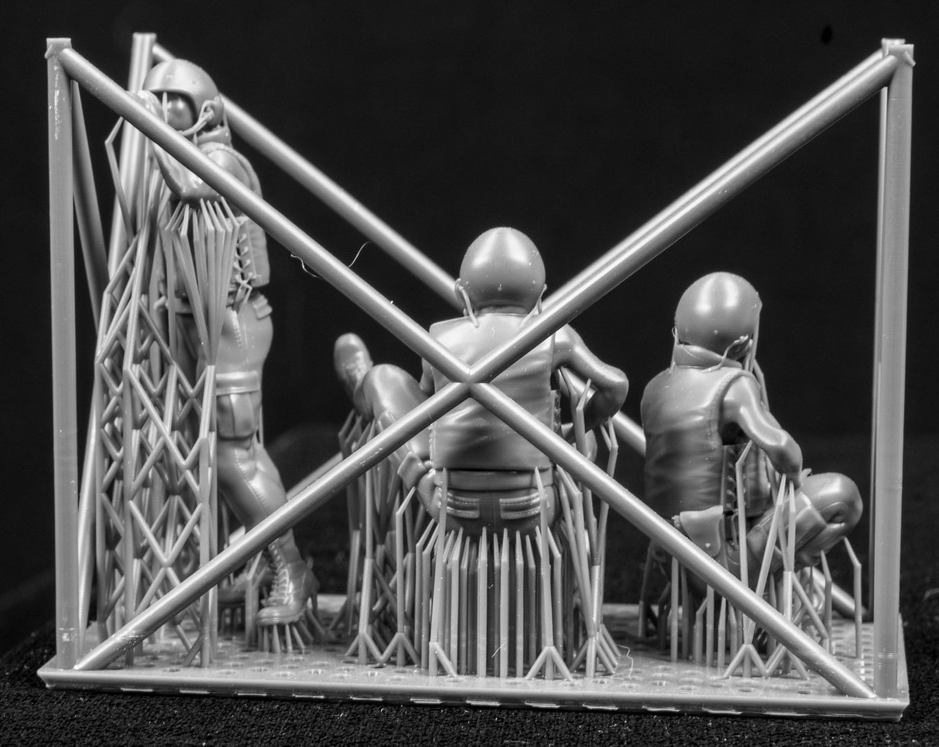 Three miniature figures in a cradle on a black background