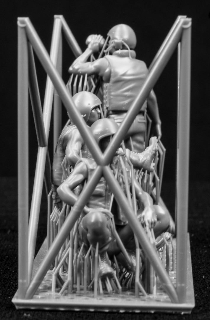 Three miniature figures in a cradle on a black background