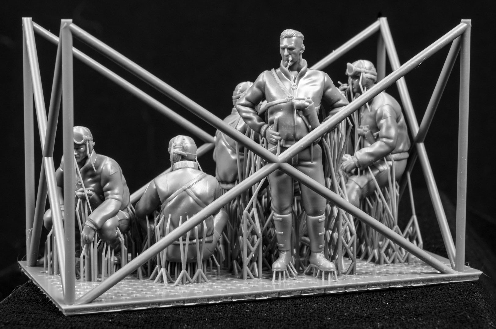 Model figures of people in tank clothing with a frame structure on a black background