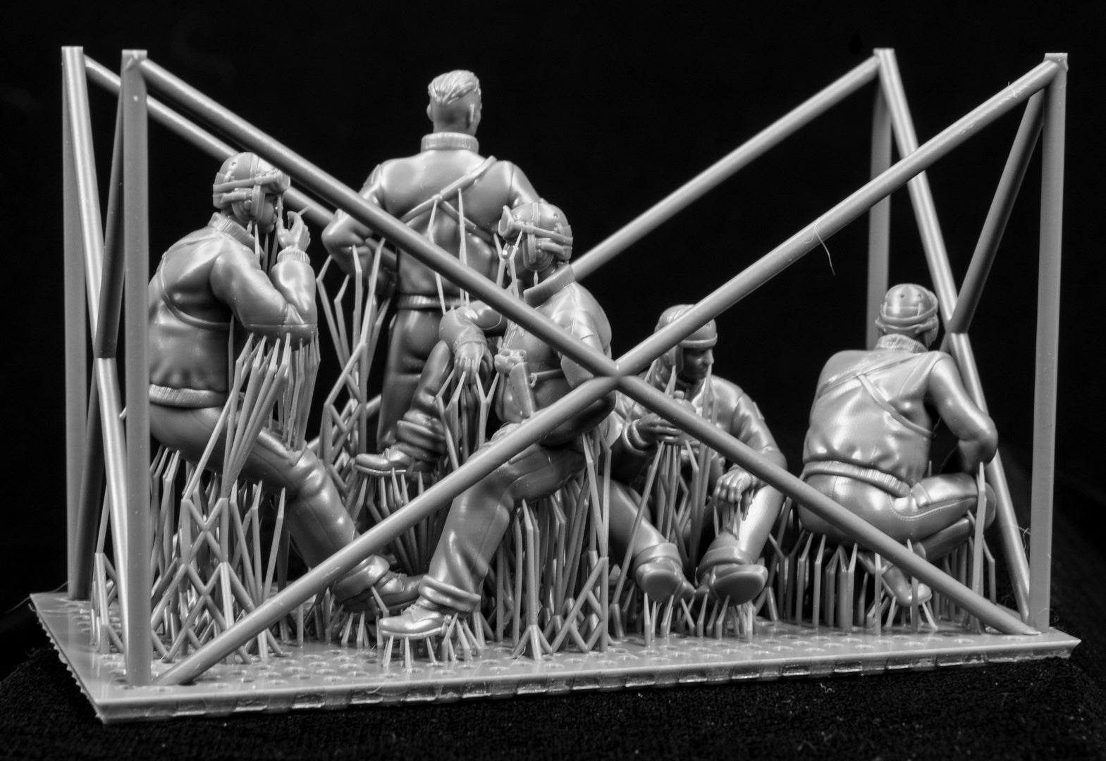 Model figures of people in tank clothing with a frame structure on a black background