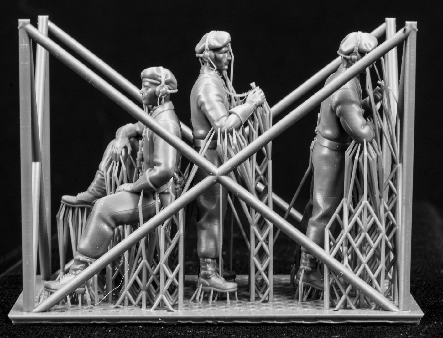 Three  miniature figures in a cradle on a black background