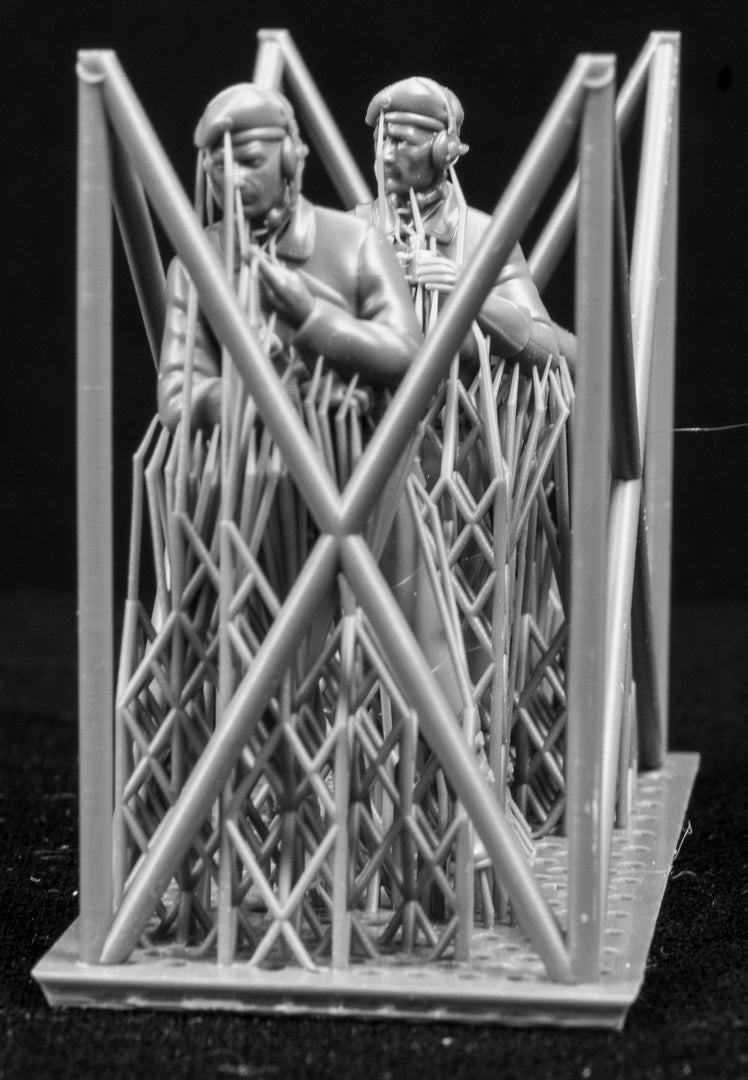 Three  miniature figures in a cradle on a black background