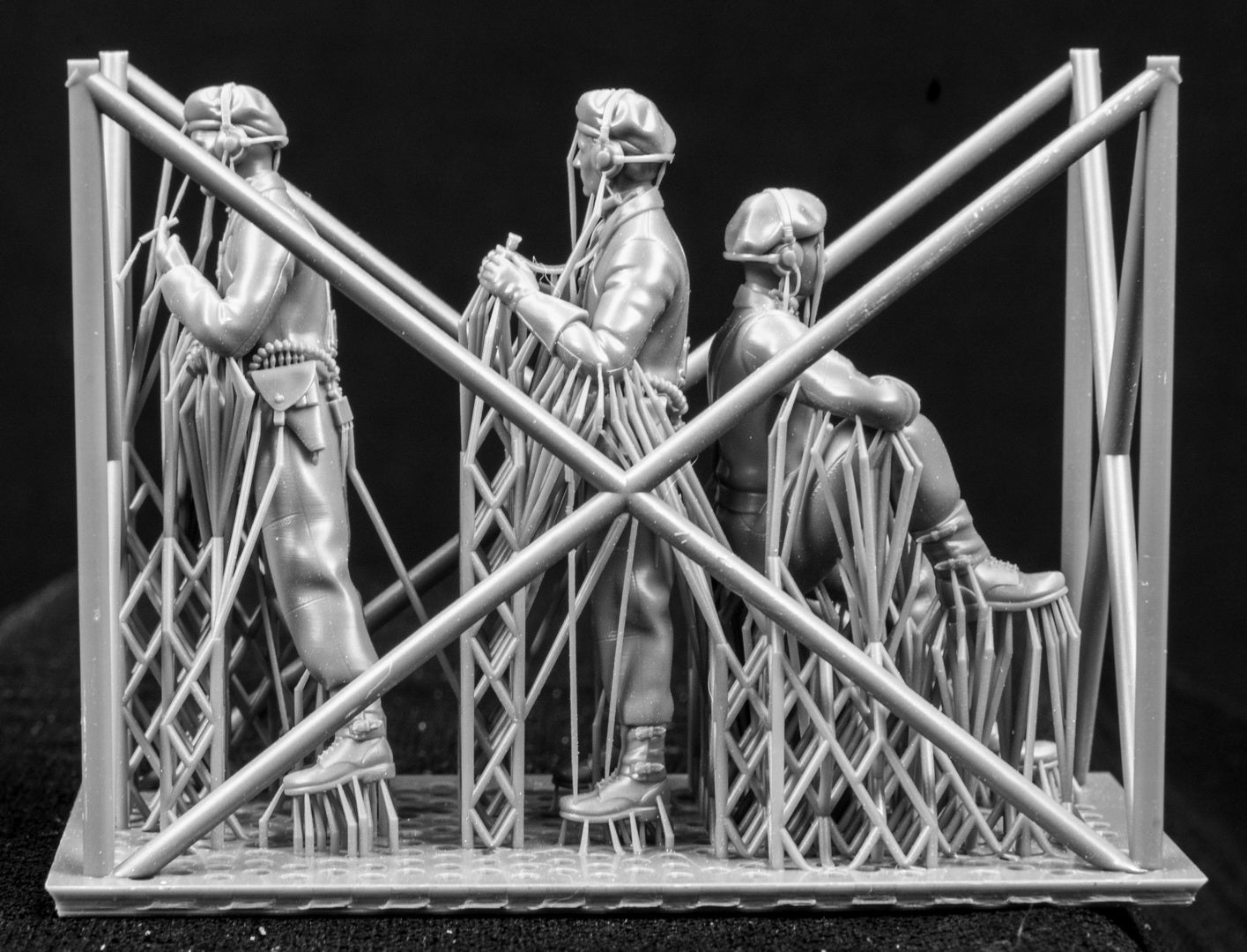 Three  miniature figures in a cradle on a black background