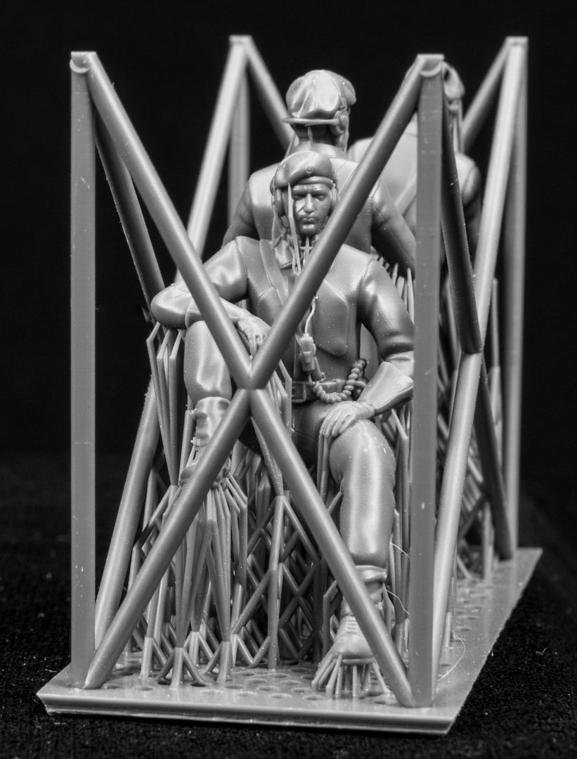 Three  miniature figures in a cradle on a black background