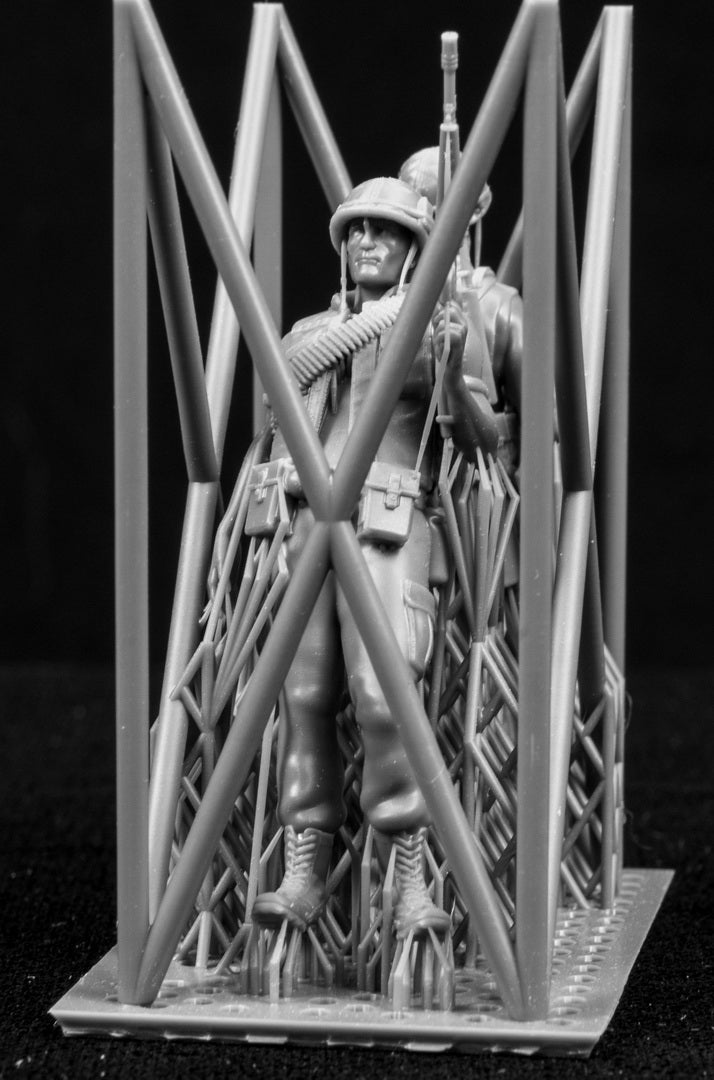 Model figures of soldiers workers behind a protective grid on a black background