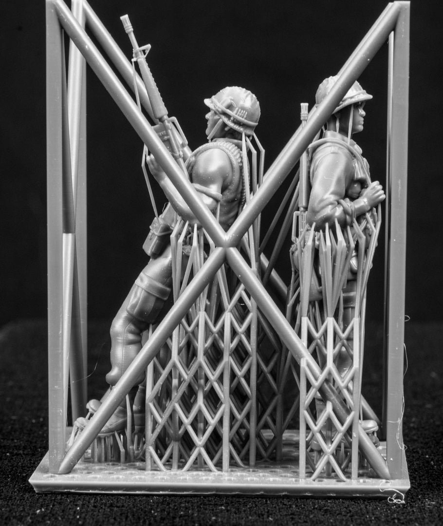 Model figures of soldiers workers behind a protective grid on a black background
