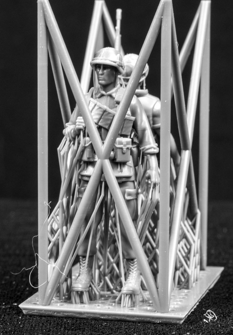 Model figures of soldiers workers behind a protective grid on a black background