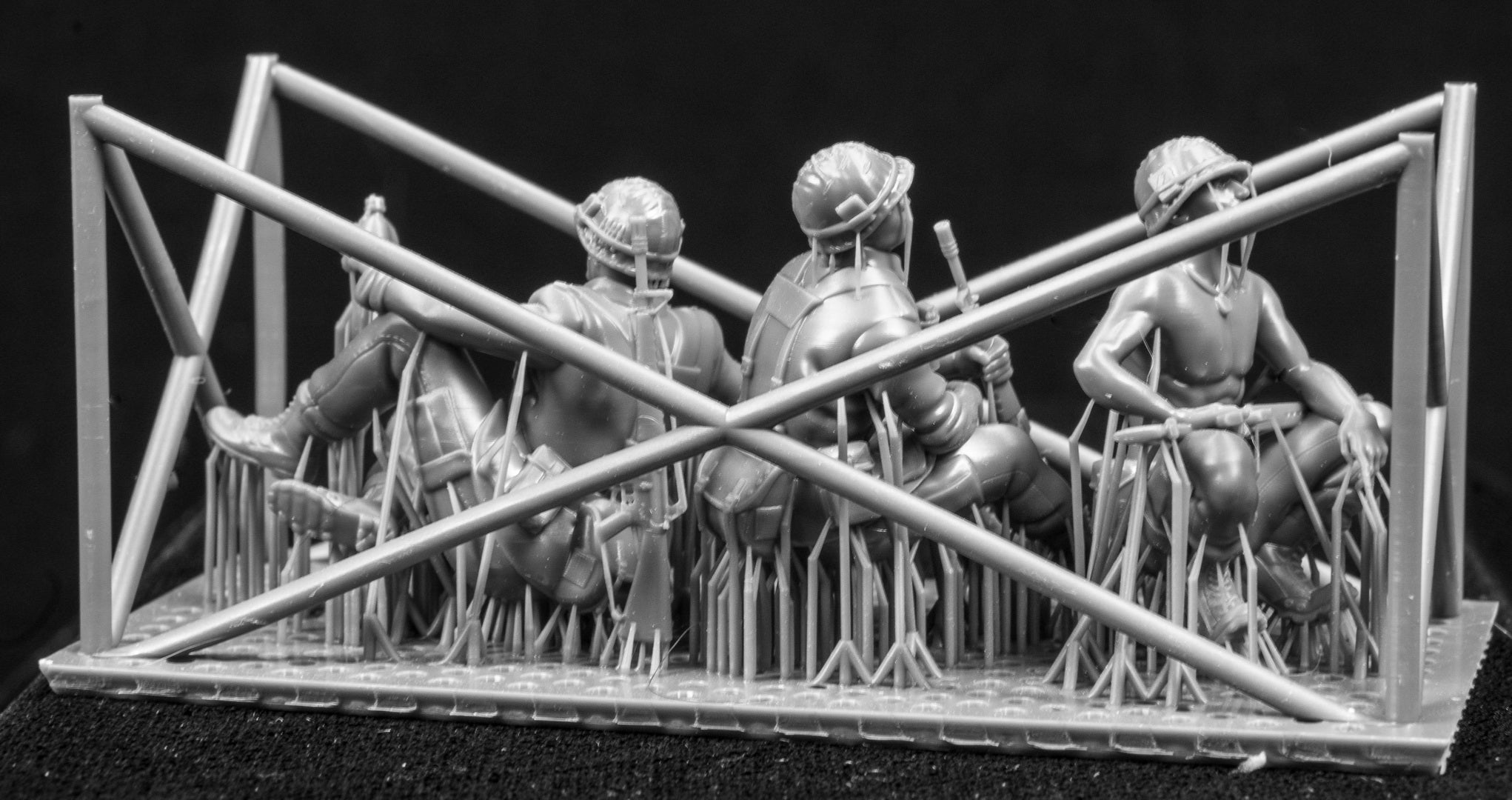 Model figures of soldiers workers behind a protective grid on a black background