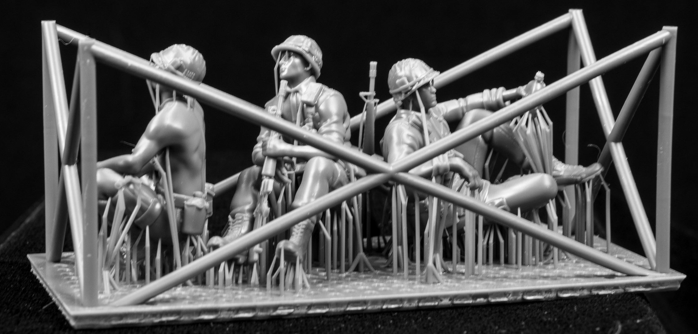 Model figures of soldiers workers behind a protective grid on a black background