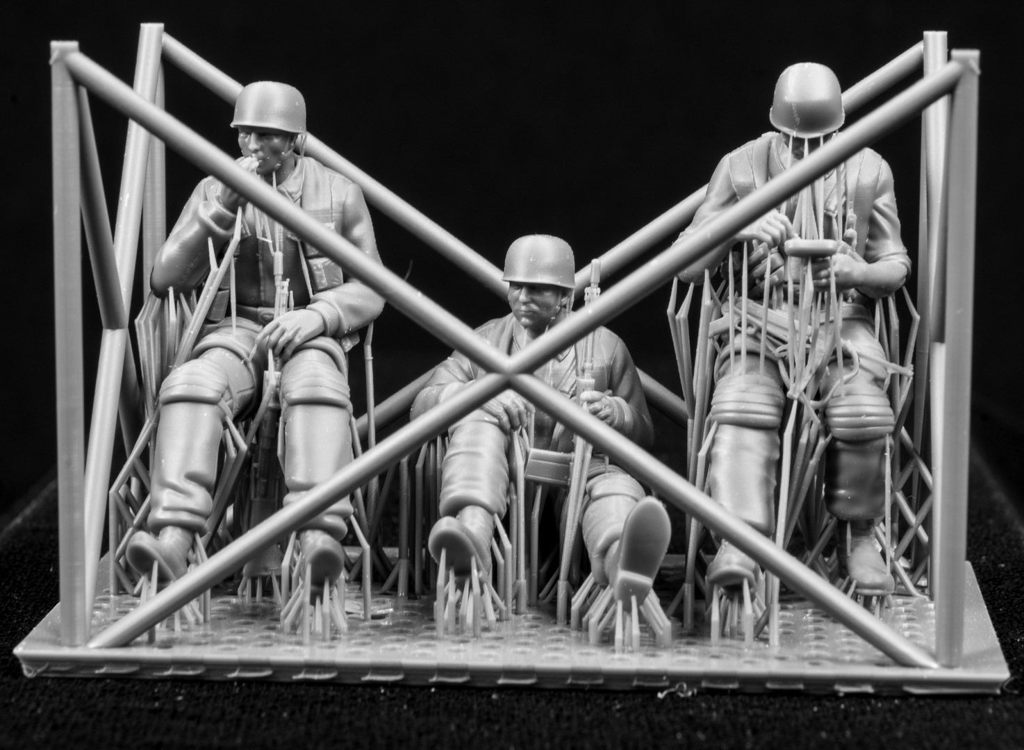 Three miniature figures in a cradle on a black background