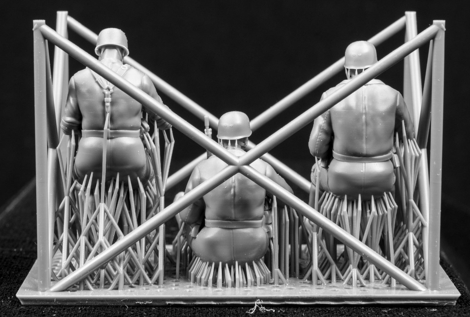 Three miniature figures in a cradle on a black background