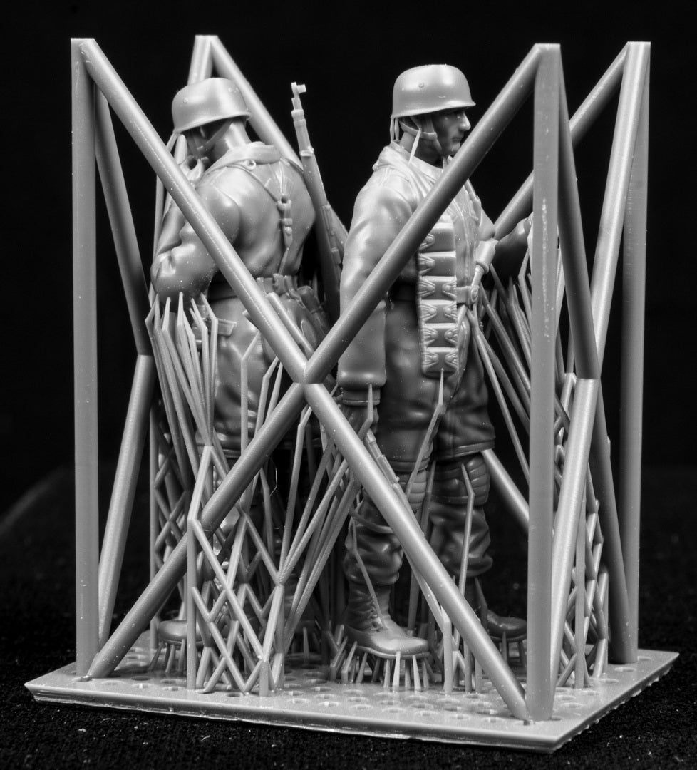 Two miniature figures in a cradle on a black background