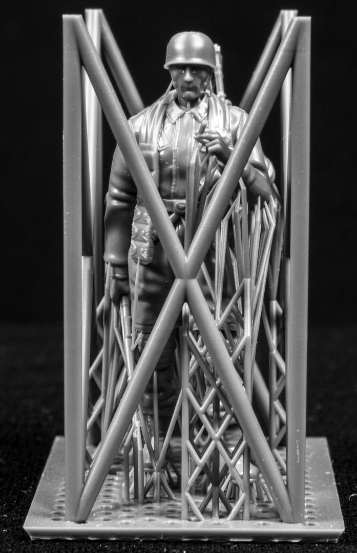Two miniature figures in a cradle on a black background