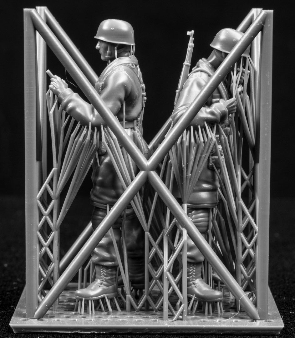 Two miniature figures in a cradle on a black background