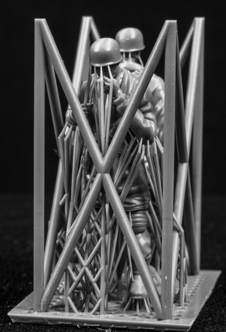 Two miniature figures in a cradle on a black background