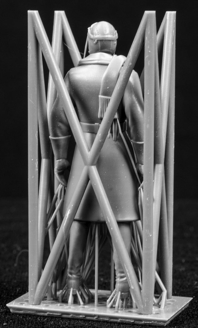 Model figure of a pilot behind a protective grid on a black background