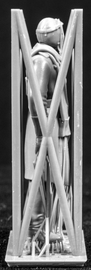 Model figure of a pilot behind a protective grid on a black background