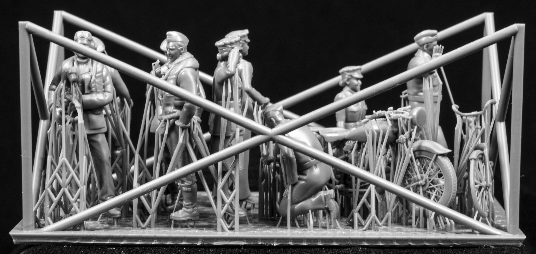 A collection of 3D printed figures, motorcycle and bicycle on a frame with a black background.