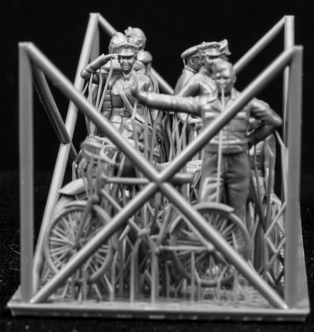 A collection of 3D printed figures, motorcycle and bicycle on a frame with a black background.