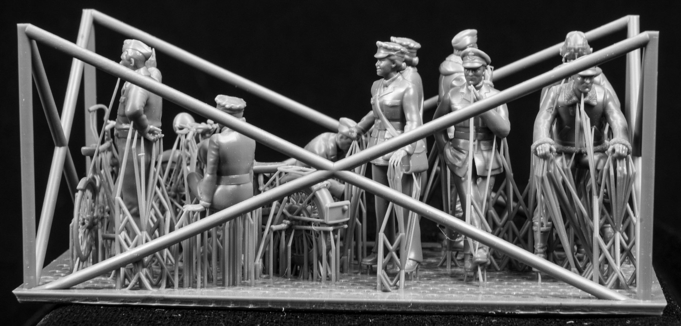 A collection of 3D printed figures, motorcycle and bicycle on a frame with a black background.