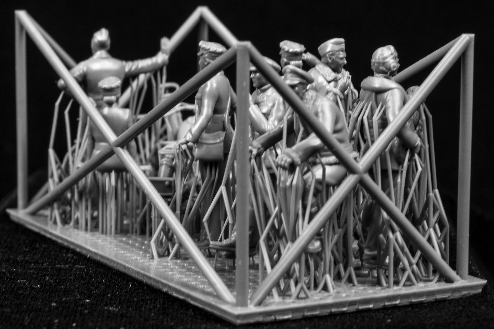 A collection of 3D printed figures, motorcycle and bicycle on a frame with a black background.