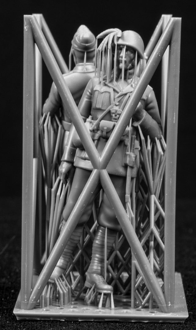 Two miniature figures in a cradle on a black background