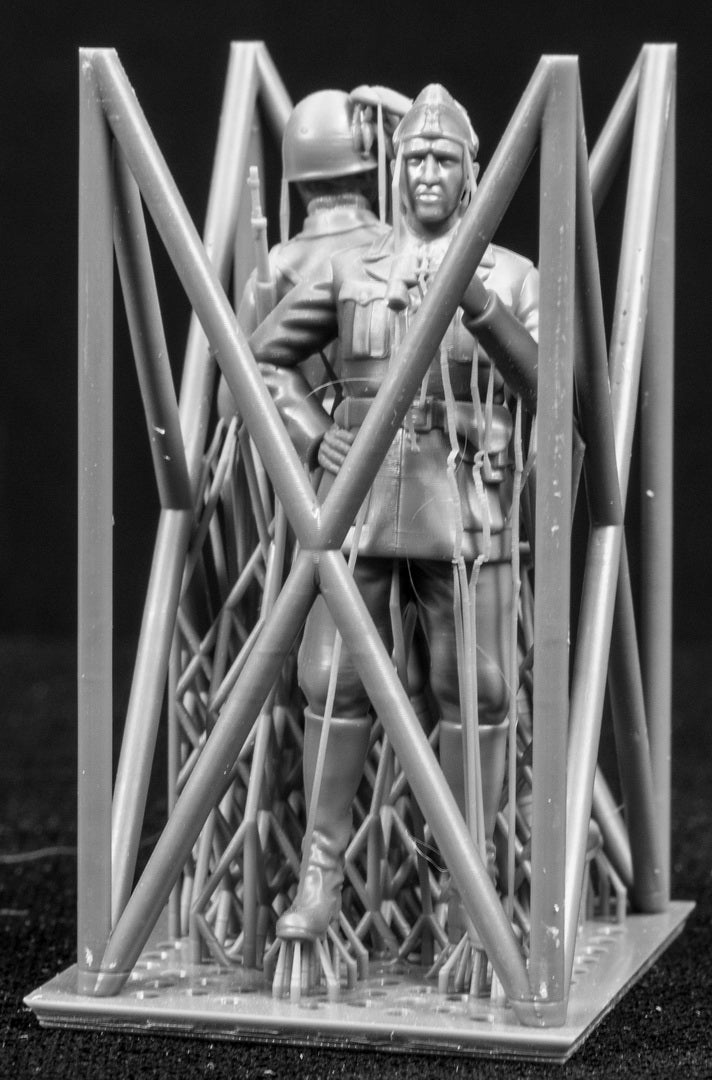 Two miniature figures in a cradle on a black background