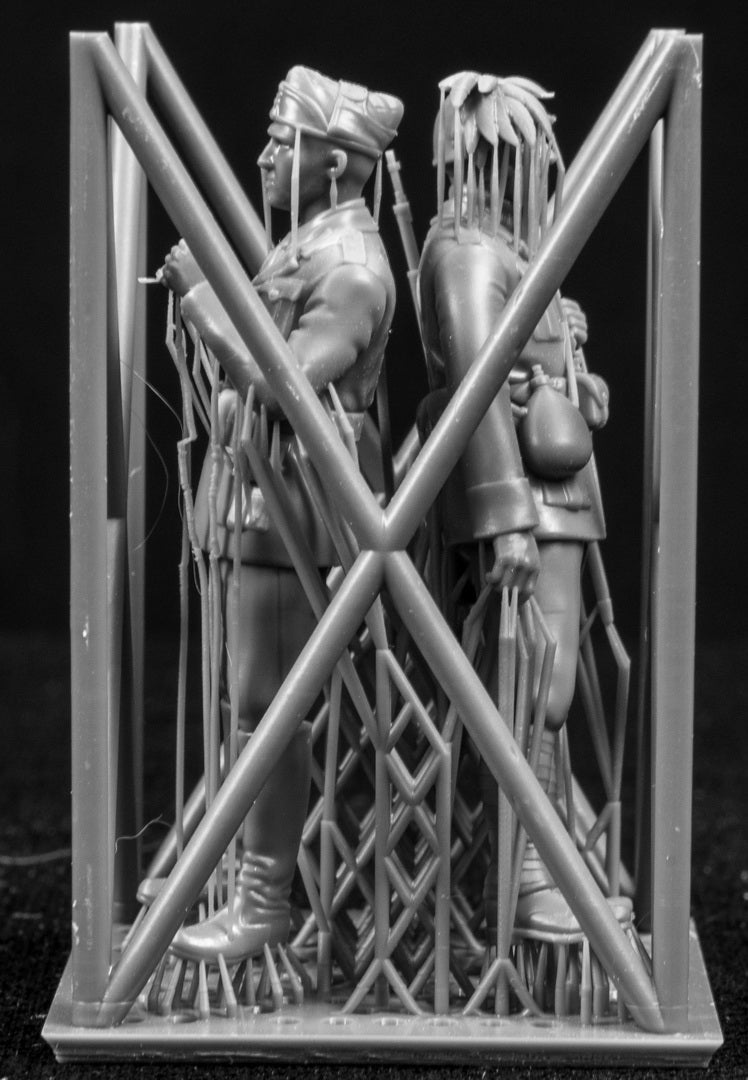 Two figurines in a cage-like structure on a black background