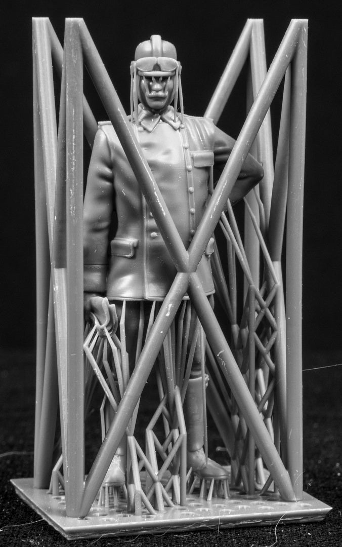 Model figure of a pilot behind a protective grid on a black background