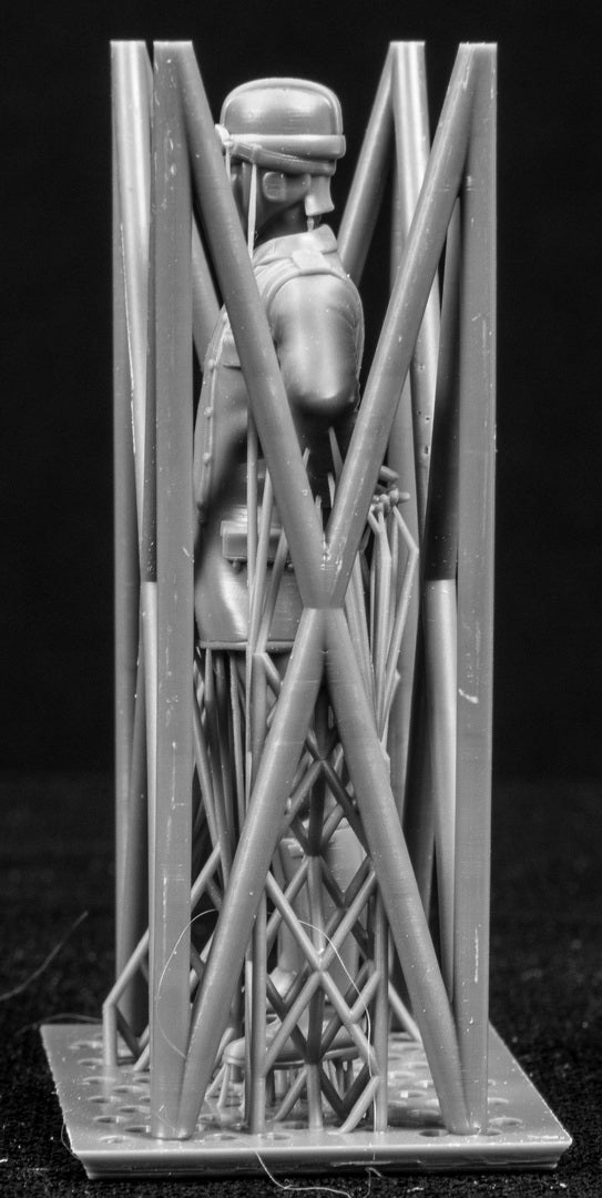 Model figure of a pilot behind a protective grid on a black background