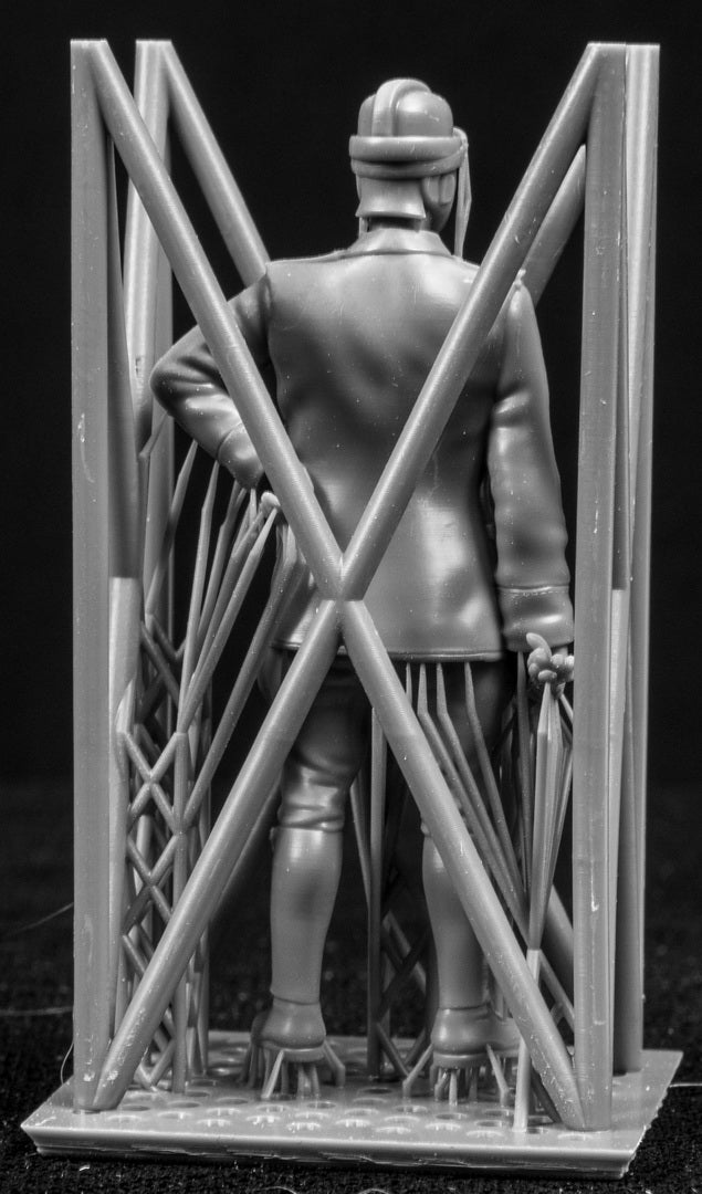 Model figure of a pilot behind a protective grid on a black background