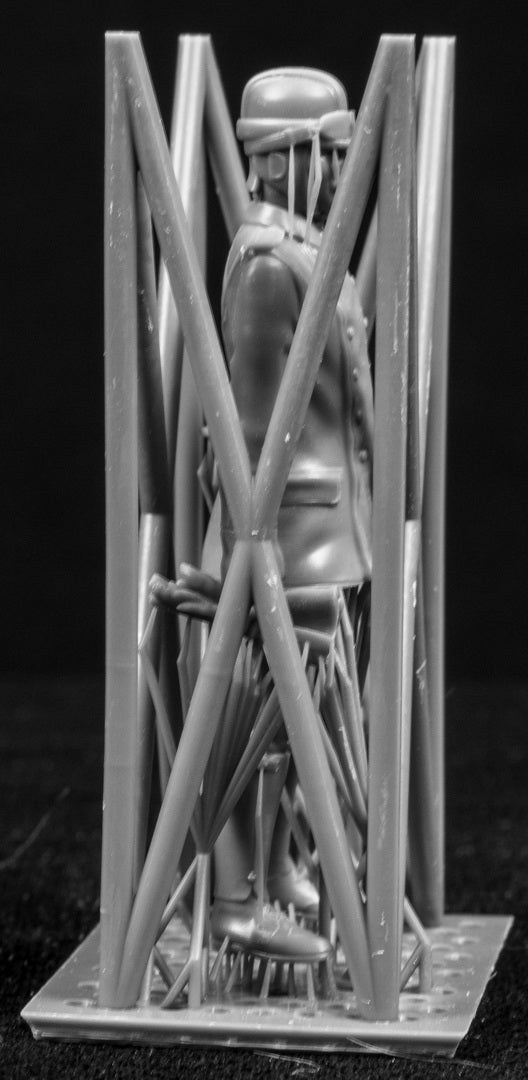 Model figure of a pilot behind a protective grid on a black background
