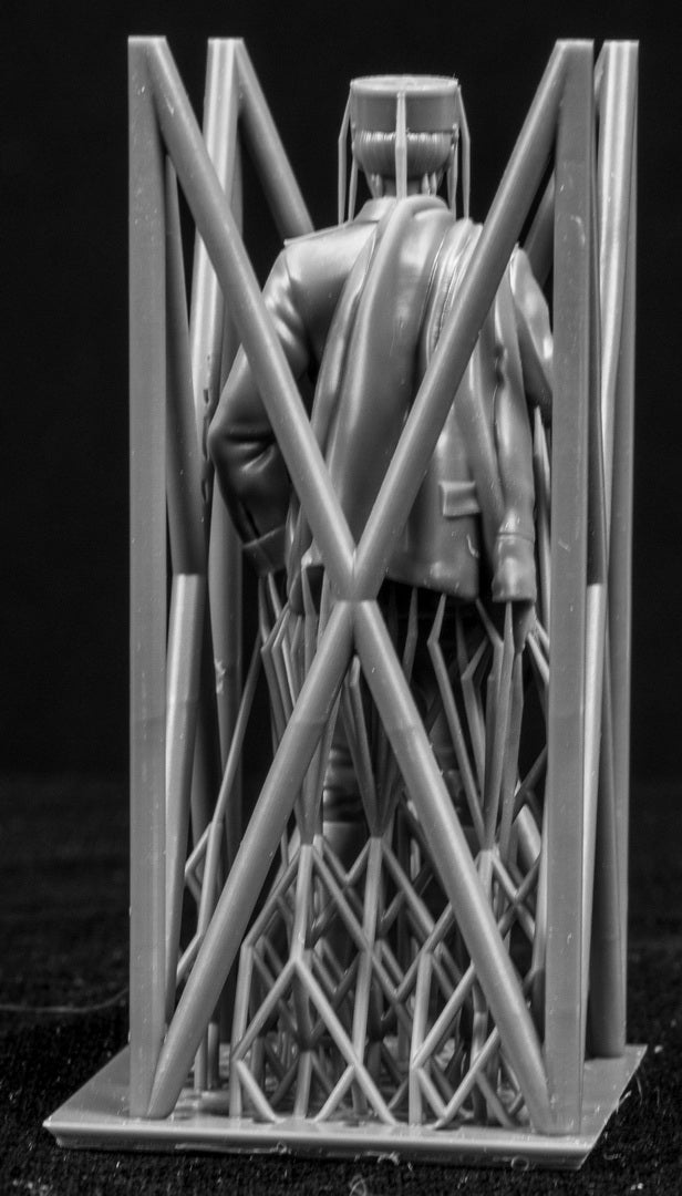 Model figure of a pilot behind a protective grid on a black background
