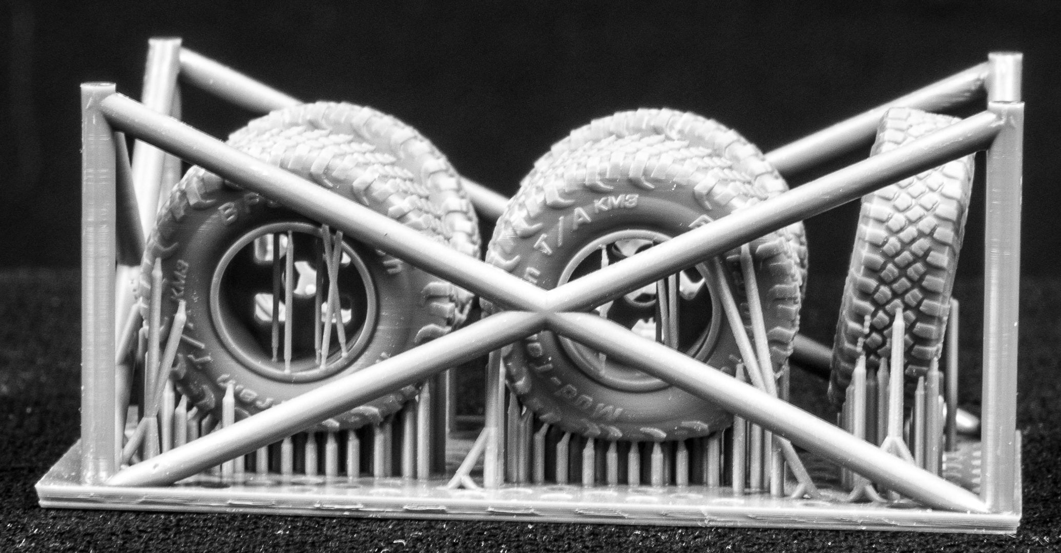 Four MRZR Weighted Wheel Set (On-Road Pattern) plus one spare on a 3D printed frame with a black background