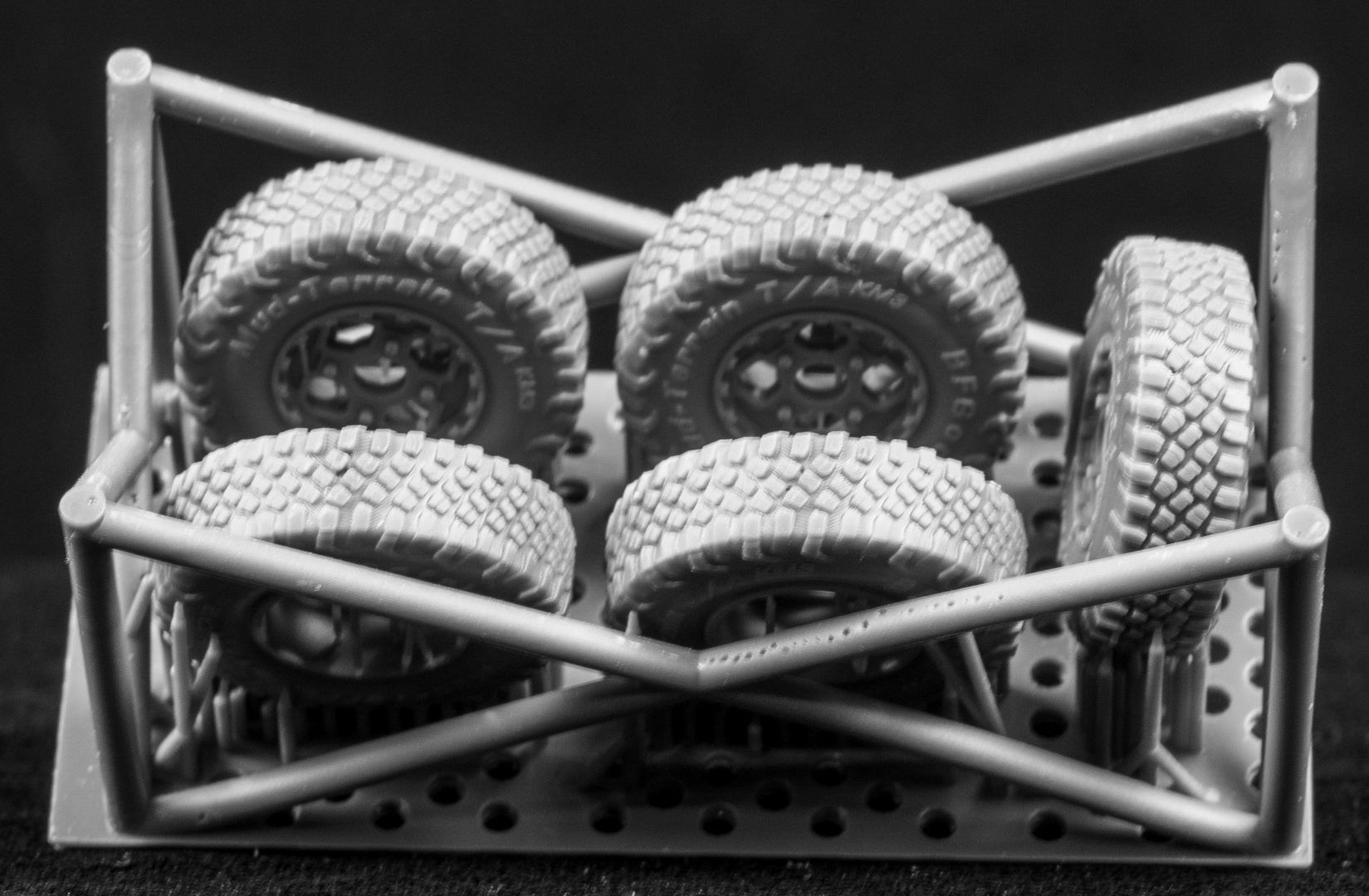 Four MRZR Weighted Wheel Set (On-Road Pattern) plus one spare on a 3D printed frame with a black background