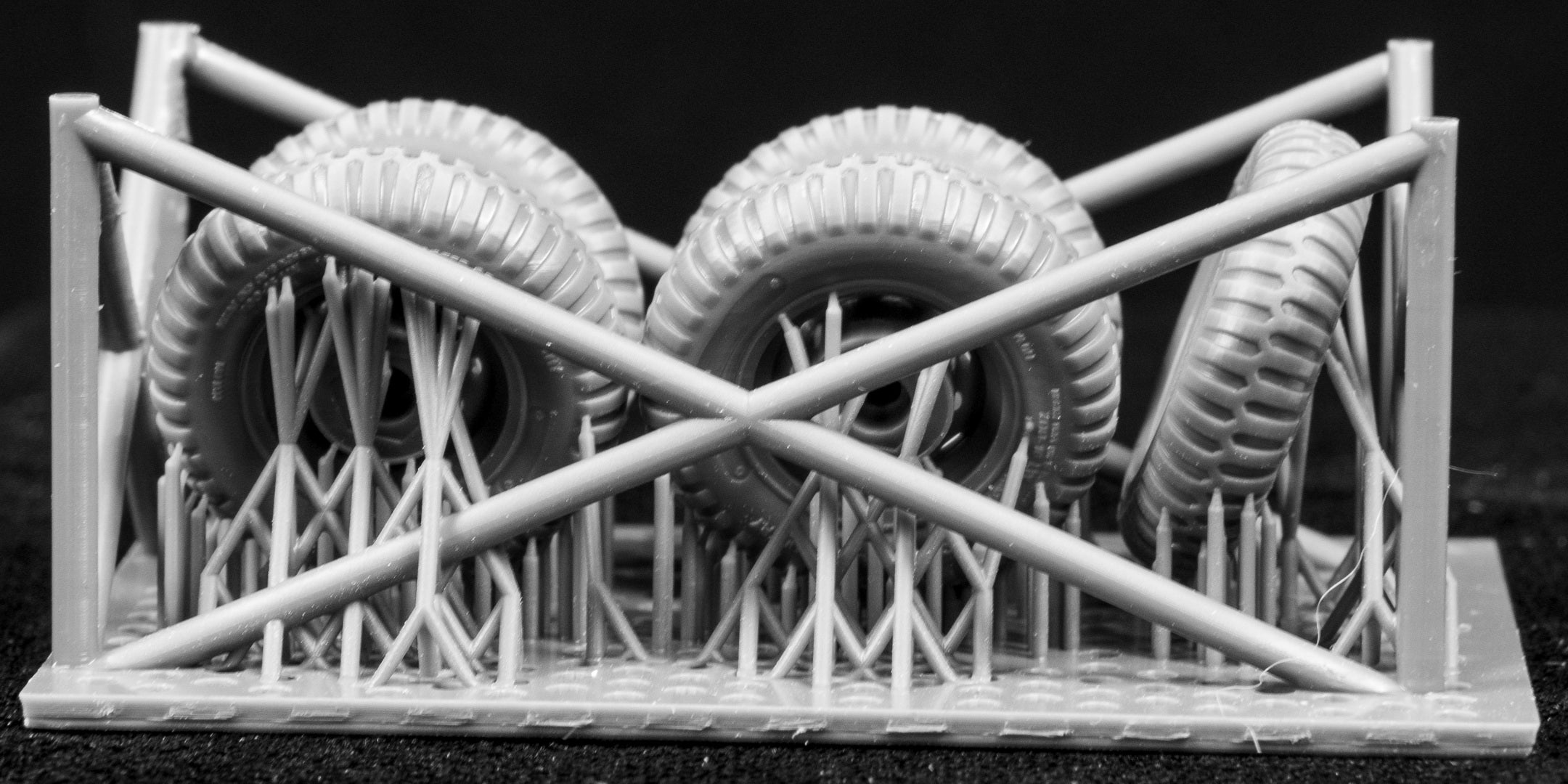 3D-printed model of  car tires and a track structure on a black background