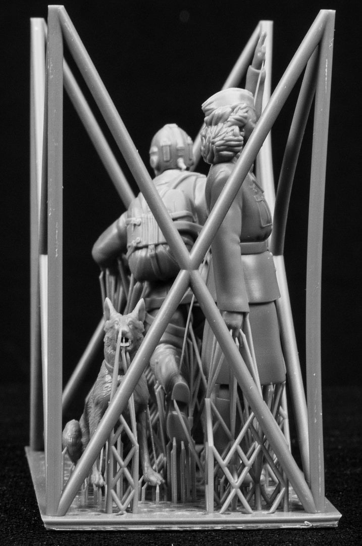 Two figurines in a cage-like structure on a black background