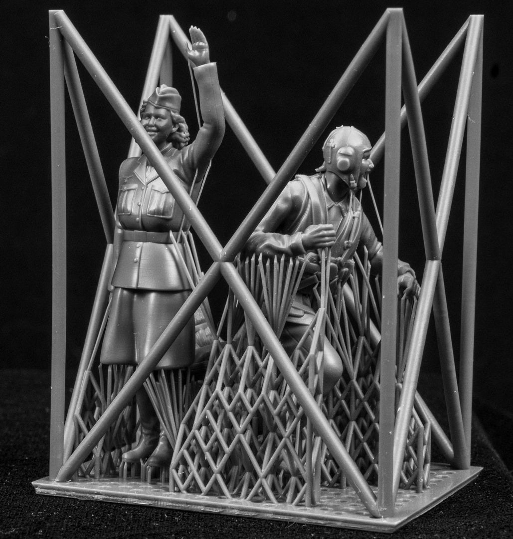 Two figurines in a cage-like structure on a black background
