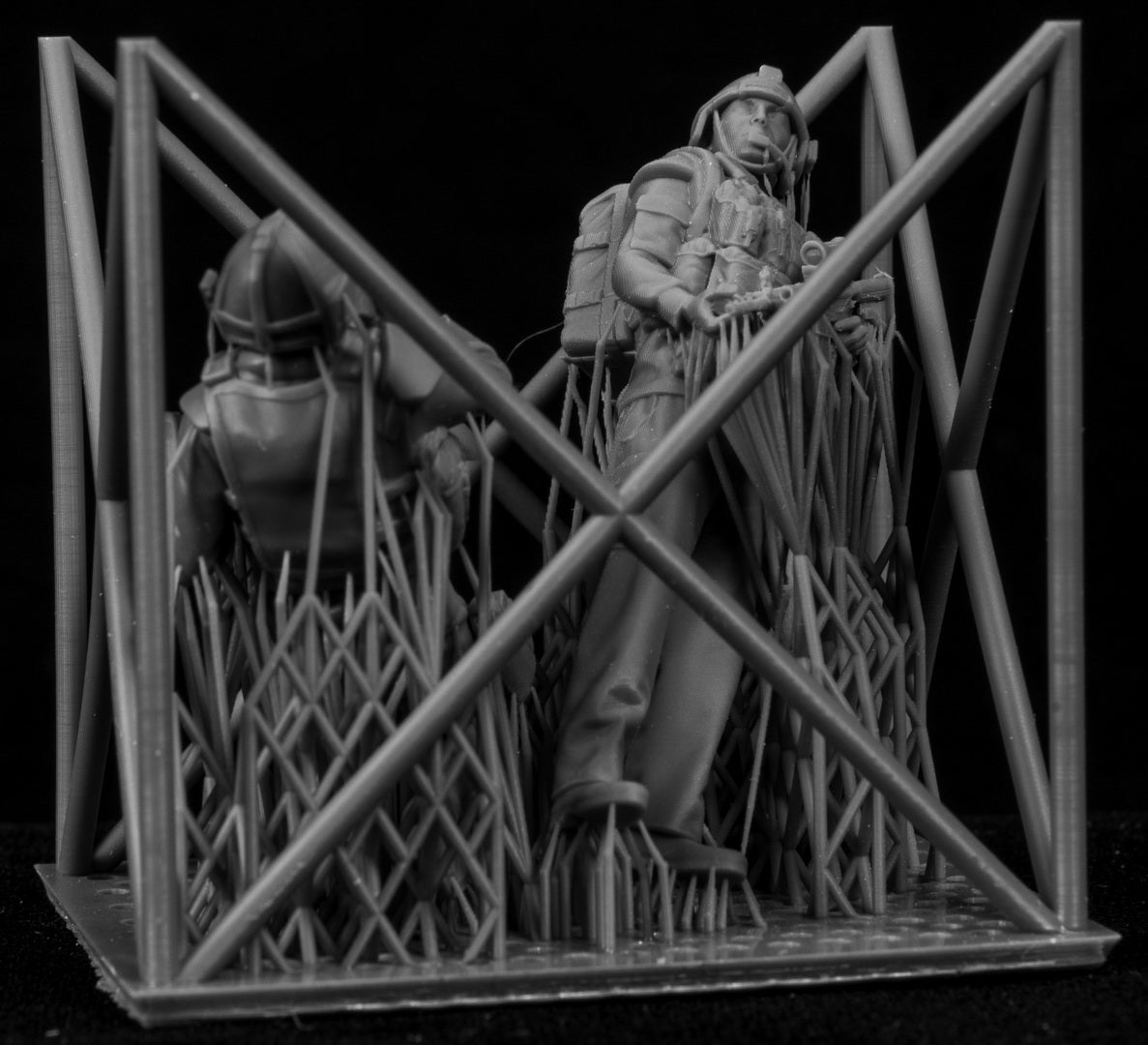 Model of two figures in a cage-like structure on a black background